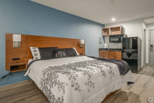 a bedroom with a bed, desk and refrigerator at The  Studios At Channelview