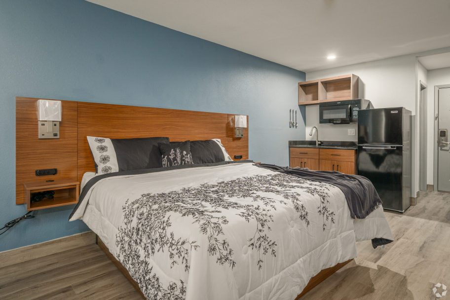 a bedroom with a bed, desk and refrigerator at The  Studios At Channelview